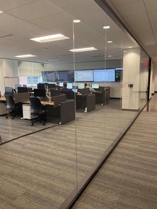 Office control room with multiple monitors seen behind a glass wall