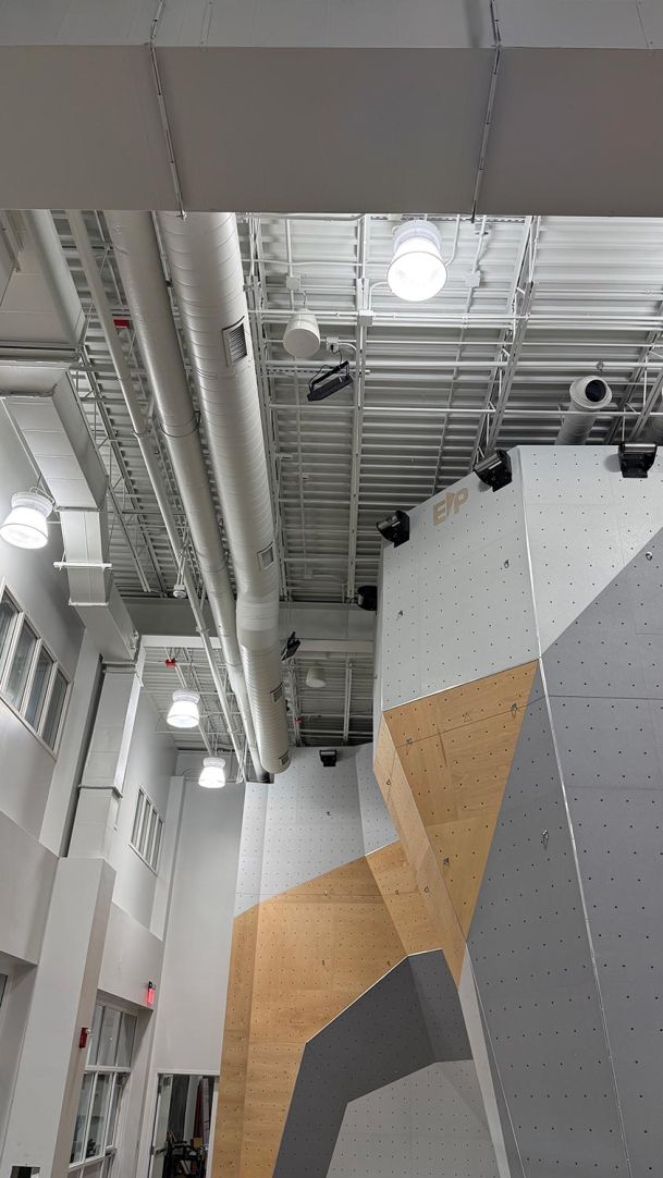 High ceiling indoor climbing wall structure alongside industrial ventilation ducts
