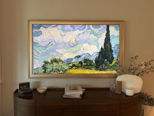 Framed television displaying landscape art mounted above a wooden console table