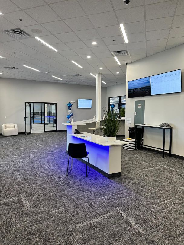 Modern reception desk illuminated with blue accent lighting and wall-mounted screens