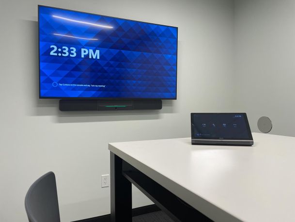 Modern conference room display screen with a video call control panel on the table