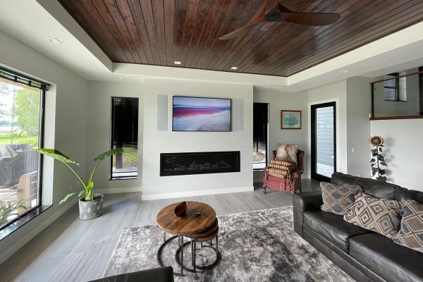 Modern living room with a TV mounted over a fireplace, dark leather sofa, and round coffee tables