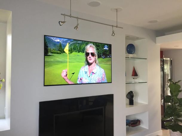Wall-mounted television above a fireplace flanked by built-in display shelves
