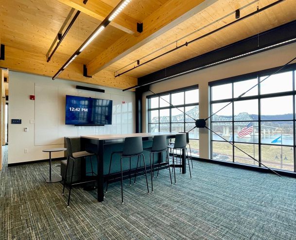 Meeting space with tall table, high chairs, and large windows overlooking a bridge