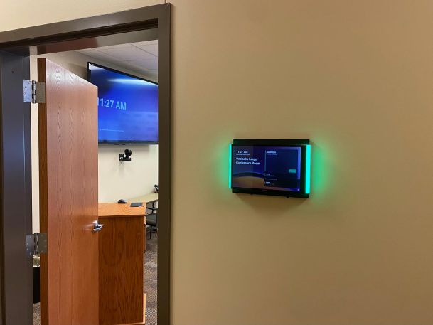 Wall-mounted digital room scheduling display with green LED status lights