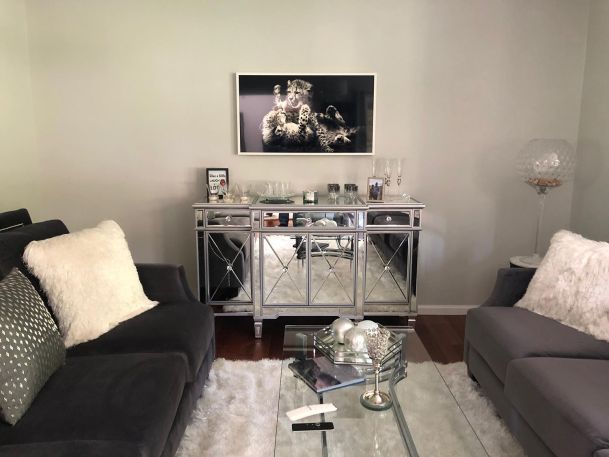 Living room featuring grey velvet sofas, mirrored console, and glass coffee table