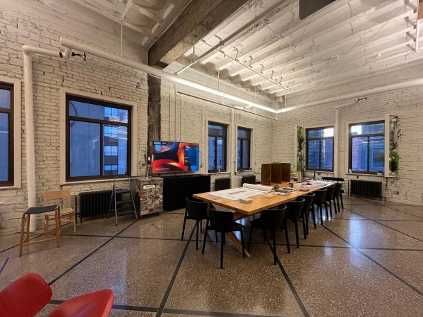 Industrial style conference room with exposed white brick walls and a large wooden table