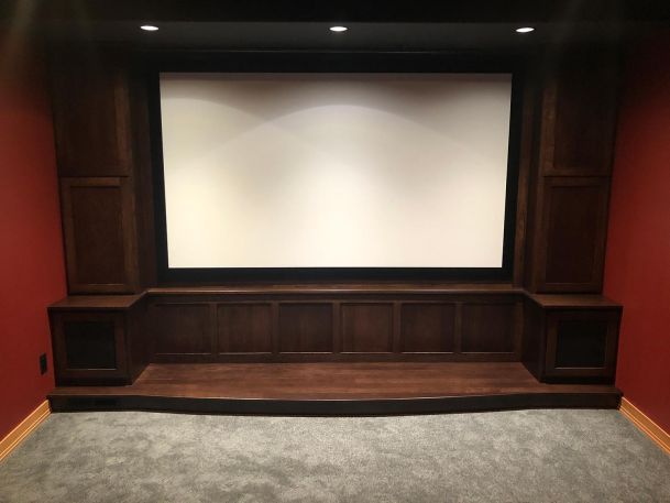 Home theater setup with a projection screen surrounded by custom wood cabinets