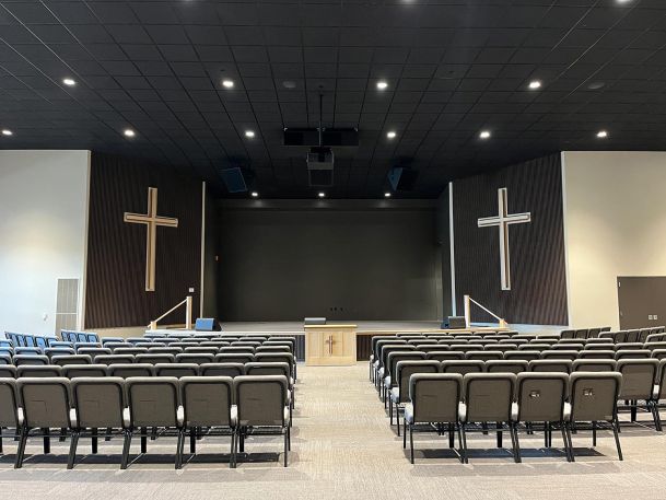 Modern sanctuary with rows of grey chairs facing a stage with two large wooden crosses