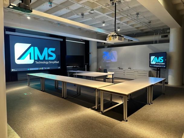Large conference room with modular tables and projector screens