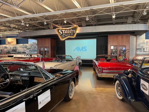 Classic car showroom displaying vintage convertibles under a illuminated neon sign